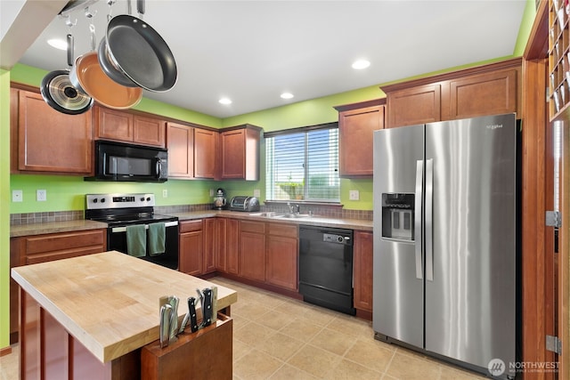kitchen with black appliances, butcher block countertops, recessed lighting, a sink, and brown cabinetry