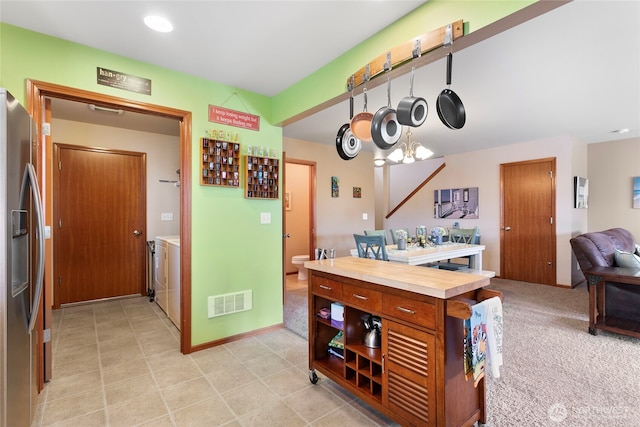 kitchen featuring washer and dryer, stainless steel refrigerator with ice dispenser, open shelves, brown cabinets, and open floor plan