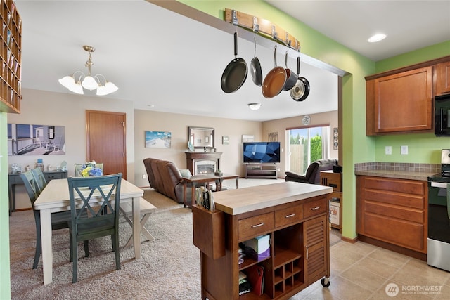 kitchen with stainless steel electric range oven, a chandelier, brown cabinets, black microwave, and open floor plan