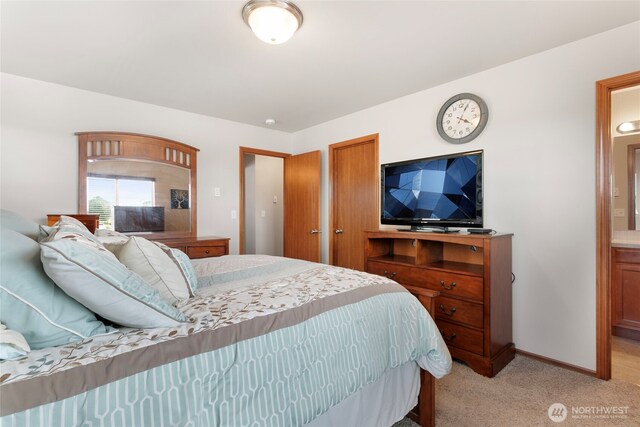 bedroom with light carpet, connected bathroom, and baseboards