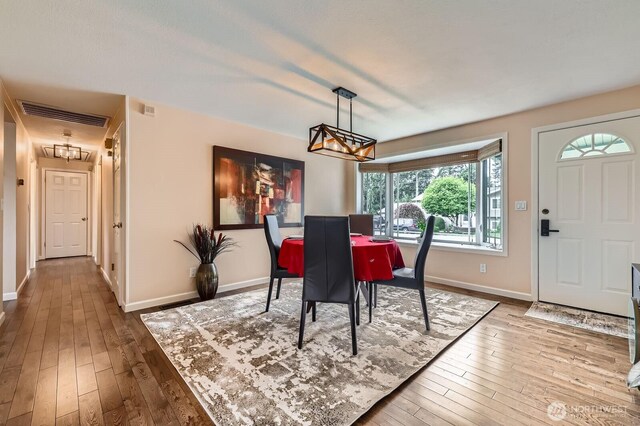 dining space with a chandelier, baseboards, and hardwood / wood-style flooring
