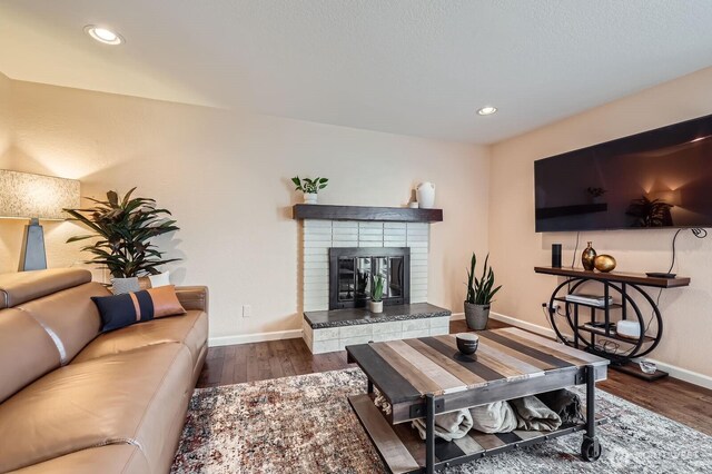 living room featuring wood finished floors, baseboards, a fireplace, and recessed lighting