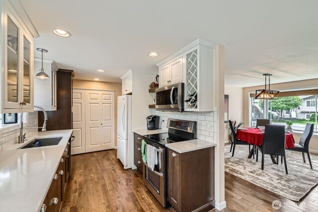 kitchen featuring stainless steel appliances, a sink, light countertops, dark wood finished floors, and tasteful backsplash