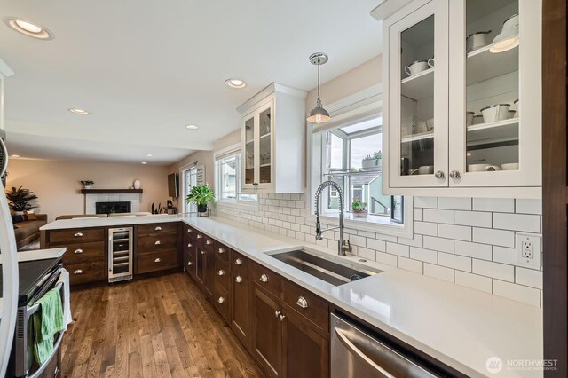 kitchen with a sink, wine cooler, dark brown cabinets, light countertops, and dark wood-style flooring