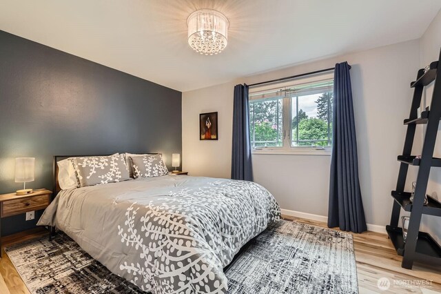 bedroom featuring wood finished floors, a chandelier, and baseboards