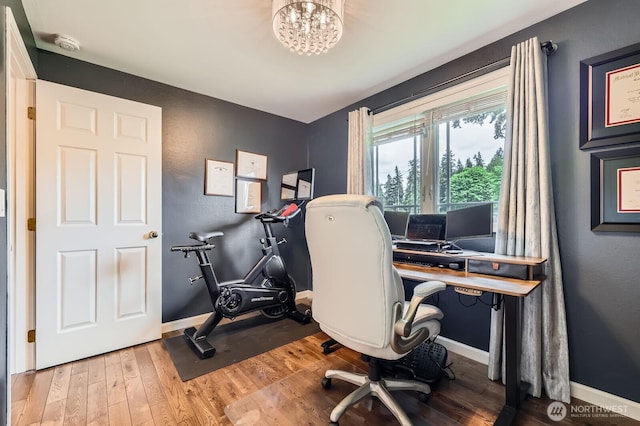 office area with wood finished floors, baseboards, and a chandelier