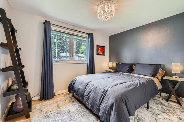 bedroom with wood finished floors, a chandelier, and baseboards