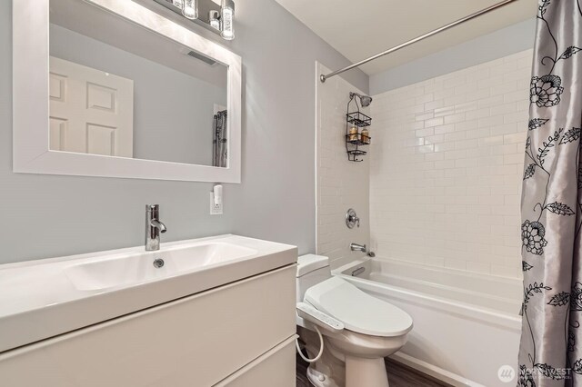bathroom with shower / bath combo with shower curtain, toilet, and vanity