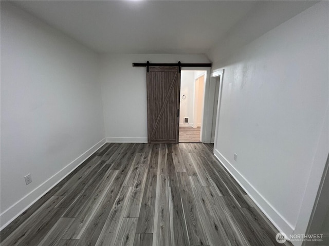 2802 Sumner Ave, Hoquiam, WA 98550 - unfurnished room featuring dark wood-style flooring, a barn door, and baseboards