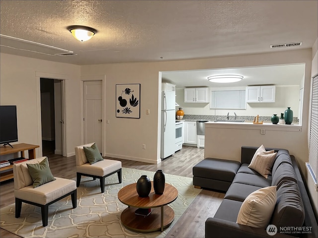 2802 Sumner Ave, Hoquiam, WA 98550 - living room featuring a textured ceiling, baseboards, visible vents, and wood finished floors