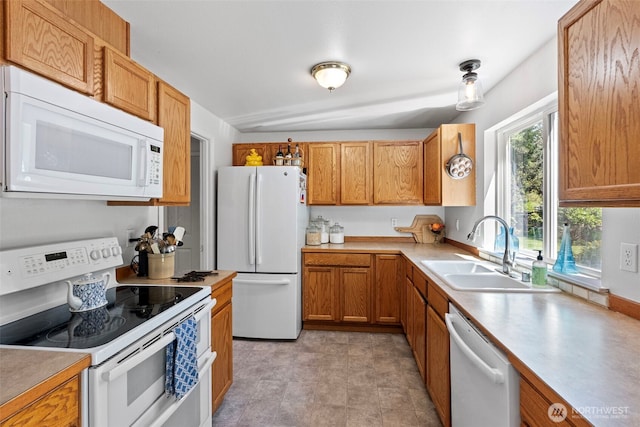 kitchen with white appliances, a sink, light countertops, and brown cabinets