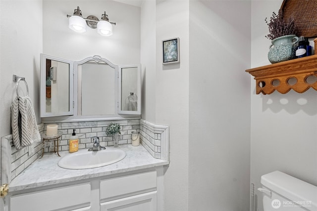 bathroom with tasteful backsplash, toilet, and vanity