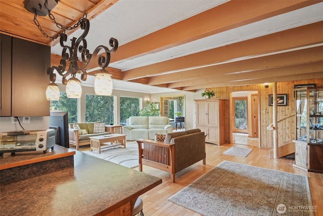 living room featuring hardwood / wood-style flooring, healthy amount of natural light, beamed ceiling, and wood walls