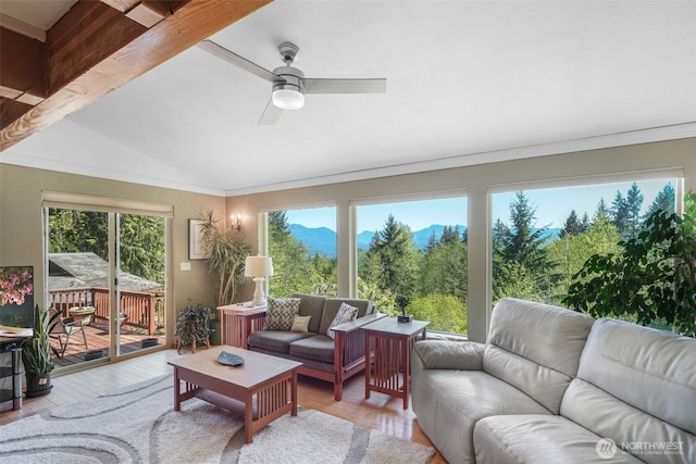 living room featuring wood finished floors, vaulted ceiling, ceiling fan, a mountain view, and ornamental molding