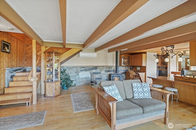 living room featuring a wood stove, wood walls, beamed ceiling, wood finished floors, and a wall unit AC