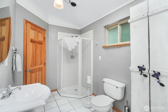 bathroom featuring a stall shower, toilet, lofted ceiling, tile patterned floors, and baseboards