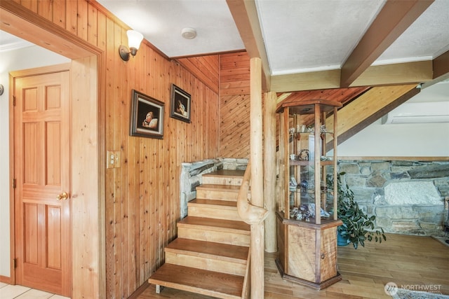 stairway featuring wooden walls, ornamental molding, and hardwood / wood-style flooring
