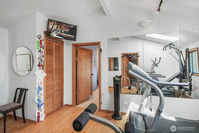 exercise room featuring wood finished floors, baseboards, and lofted ceiling