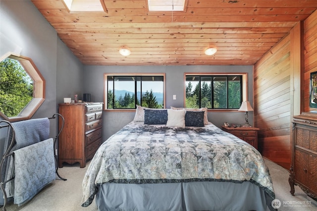 bedroom with light colored carpet, a skylight, wooden ceiling, multiple windows, and vaulted ceiling