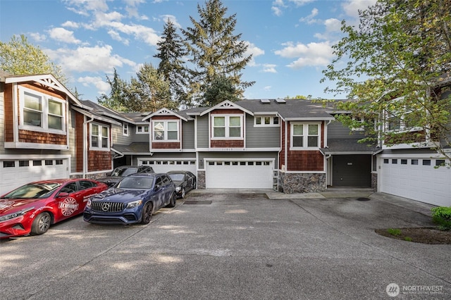 view of front facade featuring driveway, stone siding, and an attached garage