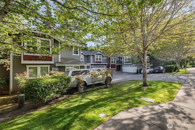 view of front of home with a front yard, asphalt driveway, a garage, and a residential view