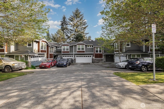 view of front of property with a garage, driveway, a residential view, and stone siding