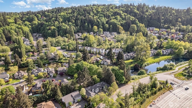 aerial overview of property's location with nearby suburban area, a nearby body of water, and a heavily wooded area