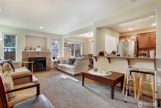living room featuring light colored carpet, a tile fireplace, a chandelier, and recessed lighting