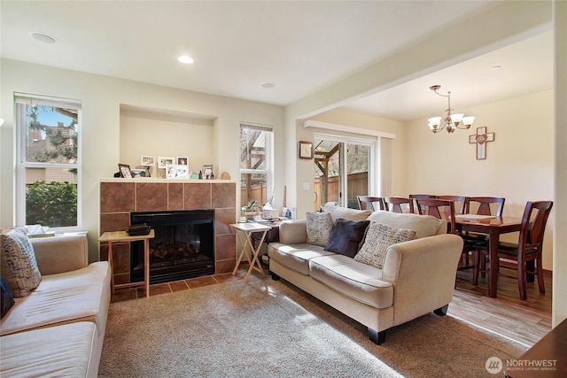 living room with healthy amount of natural light, a tiled fireplace, a chandelier, and recessed lighting