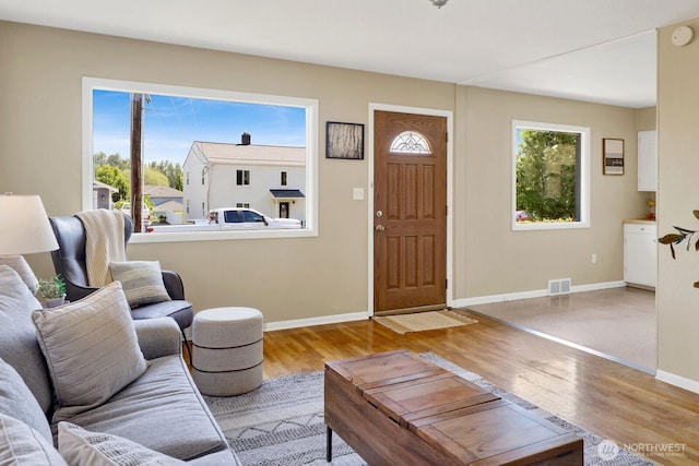living area featuring baseboards, visible vents, and wood finished floors