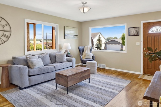 living room with baseboards, visible vents, and wood finished floors