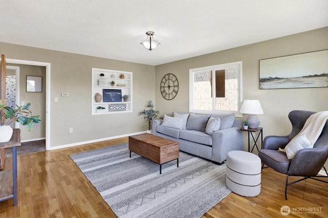 living room with built in features, baseboards, and wood finished floors