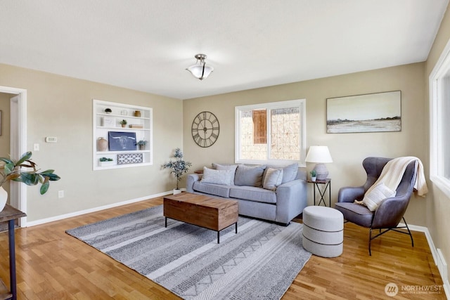 living area featuring baseboards, built in features, and wood finished floors