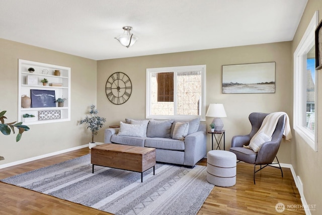 living room with built in features, baseboards, and wood finished floors