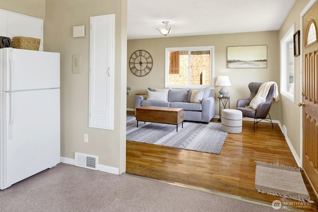 living room featuring wood finished floors, visible vents, and baseboards