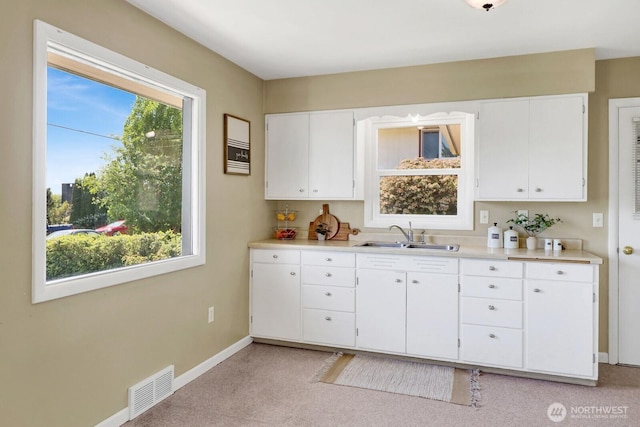 kitchen featuring a sink, white cabinets, visible vents, baseboards, and light countertops