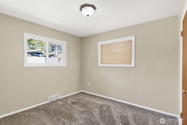 carpeted spare room featuring visible vents and baseboards