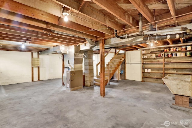 unfinished basement featuring stairway and heating unit