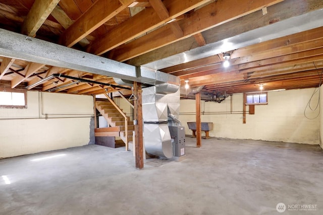 below grade area with stairway, heating unit, and a healthy amount of sunlight