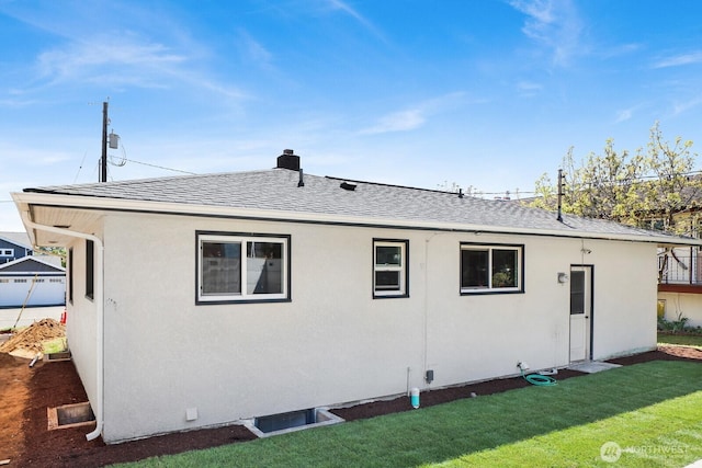 back of property featuring a shingled roof, a yard, and stucco siding