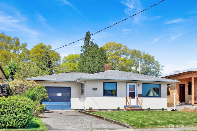 view of front of house with aphalt driveway, a garage, stucco siding, a front yard, and a chimney