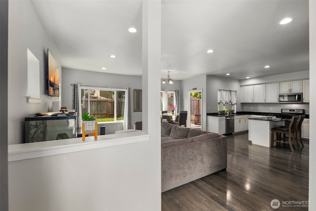 living area featuring recessed lighting, dark wood-type flooring, and a chandelier
