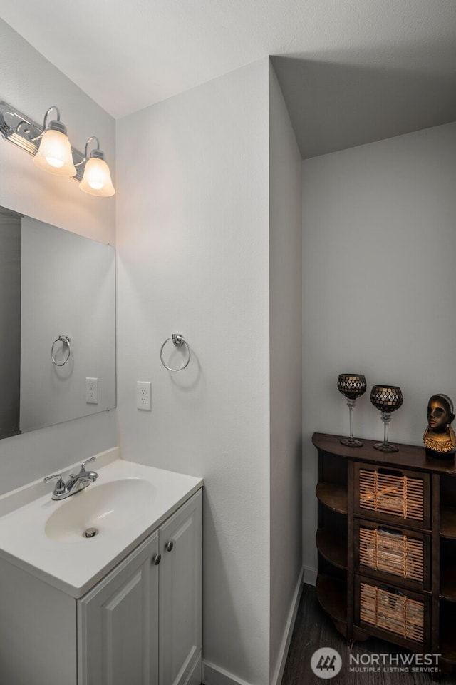 bathroom with baseboards, vanity, and wood finished floors