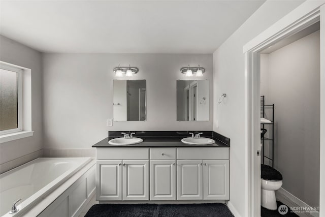 bathroom featuring a garden tub, double vanity, and toilet