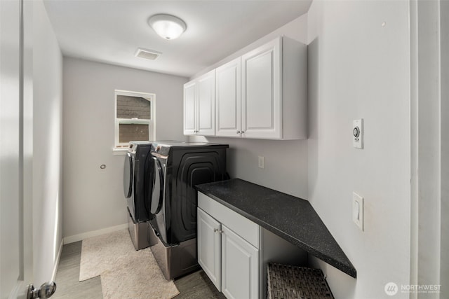 laundry room with washing machine and dryer, cabinet space, and baseboards