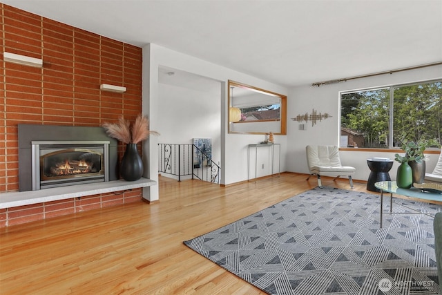 living area featuring wood finished floors, a large fireplace, and an upstairs landing