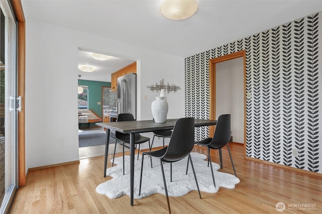 dining space with light wood finished floors and baseboards