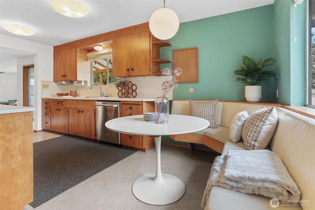 kitchen featuring dishwasher, light countertops, a sink, brown cabinetry, and open shelves