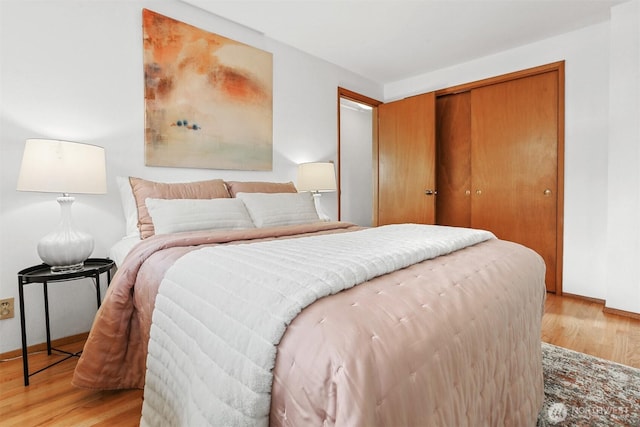 bedroom featuring light wood-type flooring, a closet, and baseboards