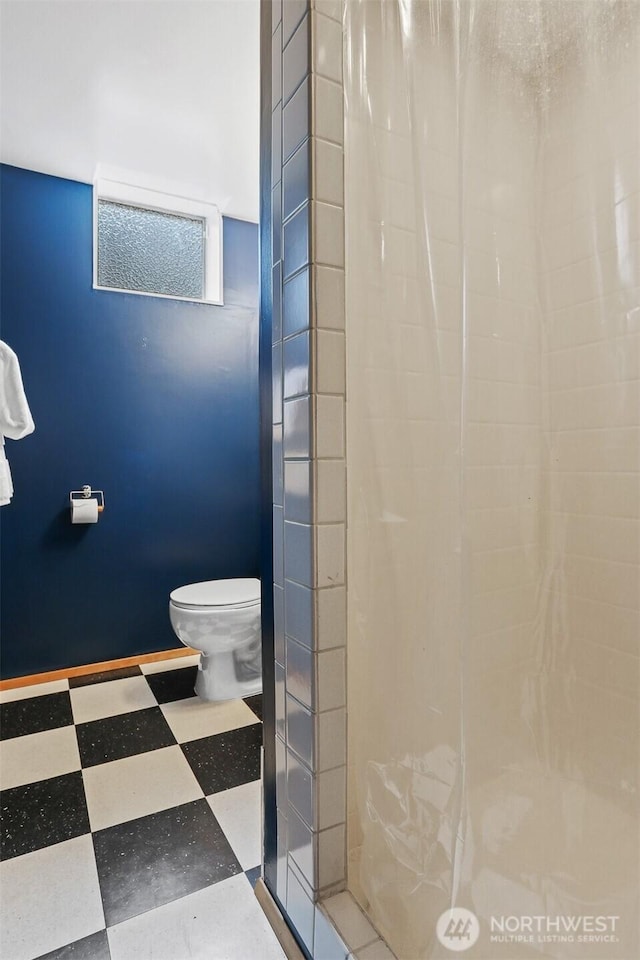 bathroom featuring tile patterned floors, a walk in shower, and toilet